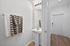 Modern minimalist bathroom with stylish lighting, pedestal sink, and chic checkered towel accents.