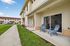 Inviting patio with two chairs, perfect for relaxing, set against a modern apartment building with a well-maintained pathway and lush greenery.