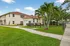 Inviting modern apartment complex with lush green lawn and palm trees, featuring beige buildings with red roofs, perfect for a serene lifestyle.