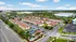 Aerial view of a charming residential community with red-roofed buildings, surrounded by lush greenery and well-maintained roads.