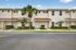 Charming townhouse exterior with manicured landscaping, palm tree accents, and a bright, inviting facade.