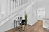 Modern entryway with sleek office nook, featuring a stylish desk under a staircase and elegant wood flooring.