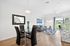 Chic open-plan living area with modern dining space, cozy seating, and large glass doors leading to a lush green outdoor view.