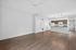 Bright and spacious open-concept apartment living area with wood flooring, featuring a modern kitchen with a granite countertop and stylish pendant lighting.