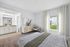 Bright bedroom featuring a luxurious built-in vanity, stylish dresser, and a large window offering lush greenery views.
