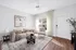 Inviting living room with elegant decor, cozy beige sofa, artistic wall picture, and natural sunlight through a large window.