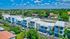 Modern townhouse complex with sleek architecture, surrounded by lush greenery and clear blue skies, offering vibrant urban living.