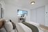 Bright and cozy bedroom featuring a comfortable bed with stylish decor, a minimalist bookshelf, and natural light streaming through a large window.