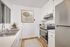 Modern kitchen with sleek stainless steel appliances, white cabinetry, and stylish geometric wall art.
