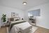 Inviting bedroom with modern decor, featuring a cozy bed, stylish artwork, and a serene atmosphere.