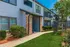 Beautiful apartment exterior with inviting pathways, well-manicured gardens, and charming balconies under a clear blue sky.