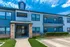 Charming two-story apartment building with modern design, featuring spacious balconies and well-maintained landscaping under a bright blue sky.