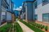 Charming apartment exterior with modern design, lush landscaping, and inviting walkways on a sunny day.