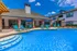 Inviting outdoor pool area with comfortable lounge chairs, vibrant blue umbrellas, and a modern clubhouse backdrop under a clear blue sky.