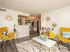 Bright and inviting living room with modern decor, featuring vibrant yellow armchairs, a sleek white coffee table, and stylish wall art, leading into an elegant dining area with a warm, open layout.