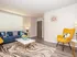 Chic living room with modern decor, featuring a blue sofa, yellow accent chair, and artistic rug in a bright and inviting space.