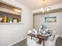 Charming dining area in modern apartment with elegant chandelier, stylish table setting, and a cozy view into a contemporary kitchen.