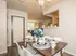 Charming dining area with a contemporary table setting, elegant chandelier, and a glimpse of a cozy and inviting living room.