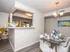 Elegant dining area with modern decor, featuring a bright kitchen nook, contemporary chandelier, and artistic wall painting.