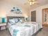 Bright and cozy bedroom featuring a plush king-sized bed with floral bedding, modern artwork, and elegant lighting.