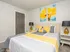 Bright and modern bedroom featuring a cozy gray and yellow color scheme, stylish artwork, and elegant bedside lamps.