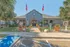 Inviting leasing office with charming architecture, vibrant landscaping, and welcoming flags.
