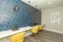 Modern co-working space with chic blue geometric wall design, featuring sleek white desks and vibrant yellow chairs for a stylish work environment.