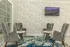 Chic and cozy sitting area with elegant gray armchairs, stylish marble-patterned tables, and a vibrant geometric accent wall, featuring an artistic blue and white rug underfoot.