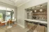 Elegant kitchen area with modern pendant lights, stylish backsplash, and a view of a serene outdoor pool through large glass doors.