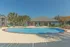 Inviting outdoor pool area with crystal-clear water, sun loungers, and tropical palm trees under a clear blue sky.