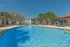 Gorgeous outdoor pool area with crystal clear water and sun loungers, surrounded by lush palm trees and modern apartment buildings.