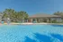 Vibrant pool area with palm trees, inviting lounge chairs, and a modern clubhouse under a clear blue sky.