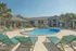 Inviting apartment complex with a sparkling pool, lush palm trees, and sunny lounge chairs for ultimate relaxation.