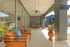 Elegant patio with vibrant orange seating, decorative blue pillows, and lush potted plants, complemented by stylish ceiling fans and modern glass doors.