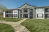 Elegant two-story apartment complex with modern architecture, spacious balconies, and lush green surroundings.