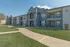 Modern apartment complex with elegant archways, spacious balconies, and lush green lawns under a clear blue sky.