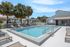 Inviting apartment complex with a pristine swimming pool, surrounded by palm trees and ample lounge chairs for relaxation.