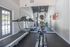 Bright apartment gym with modern treadmill, elliptical, and floor-to-ceiling mirrors offering a refreshing workout ambiance.