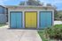 Charming storage unit with vibrant blue and yellow doors, surrounded by lush greenery and modern architecture in a cozy apartment complex.