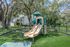 Inviting playground set amidst lush greenery, featuring a colorful slide and climbing structure at a serene apartment complex.