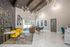 Elegant lobby with modern lighting, vibrant yellow seating, and stylish stone fireplace, featuring large windows and chic decor.
