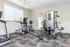 Bright and inviting gym featuring modern exercise equipment, including ellipticals and a strength training machine, ideal for a dynamic workout experience.