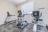 Bright and inviting fitness room with modern treadmill, elliptical, and exercise bike, perfect for a convenient workout at home.