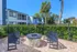 Charming outdoor seating area with sleek benches and a cozy fire pit, set in a vibrant apartment community with lush greenery and palm trees.