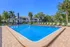 Inviting outdoor pool area surrounded by comfortable lounge chairs and lush palm trees, perfect for relaxation under the clear blue sky.