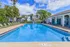 Inviting apartment complex pool area with crystal clear water, surrounded by lush palm trees and comfortable lounge chairs under a bright blue sky.