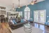 Chic living area featuring a stylish leather sofa, vibrant decor, and a modern open kitchen, enhanced by natural light from elegant glass doors leading to an outdoor view.