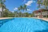 Inviting outdoor pool with crystal-clear water, surrounded by lush greenery and elegant palm trees under a bright blue sky.