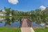 Scenic lakeside view with a charming wooden dock, surrounded by lush greenery and serene reflections.