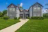 Charming residential building with elegant gray facade, surrounded by lush greenery under a bright blue sky.